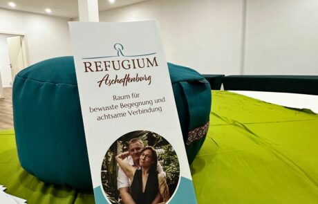 Raum in Aschaffenburg mieten – Flyer im Workshopraum 1 Flyer des Refugium Aschaffenburg auf grünem Lunghi mit Meditationskissen im Raum in Aschaffenburg mieten